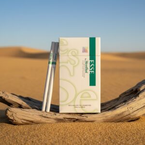 ซองบุหรี่ ESSE Menthol สีขาวแถบเขียว วางบนขอนไม้กลางทะเลทราย แสงแดดอุ่น