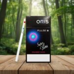 บุหรี่ Oris Pulse Strawberry Fusion ซองสีดำดีไซน์ล้ำสมัย พร้อมมวน Super Slim วางบนโต๊ะไม้ในป่า